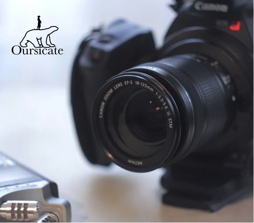 Close-up of a Canon EOS camera with an 18-135mm zoom lens, displayed with photography equipment in a professional studio setting