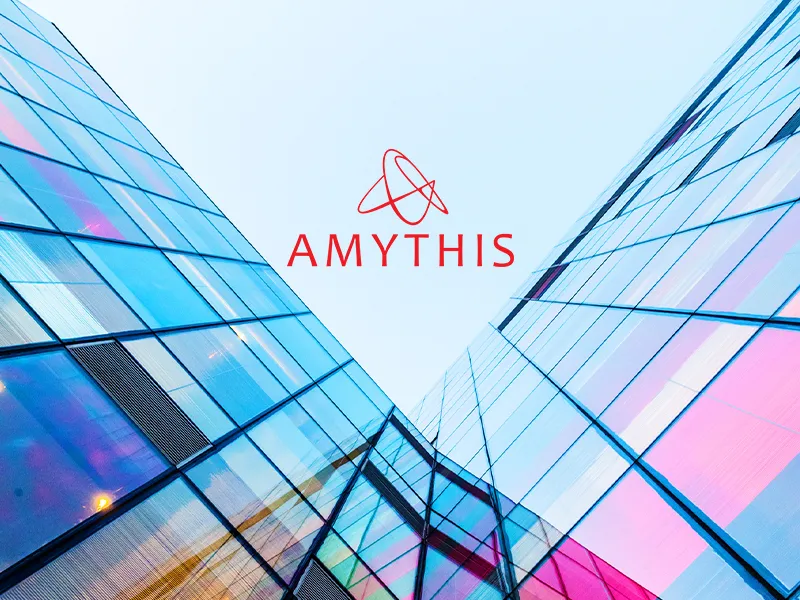 Modern glass building facade with blue and pink tones, featuring the red Amythis logo and atom symbol centered against a light sky background