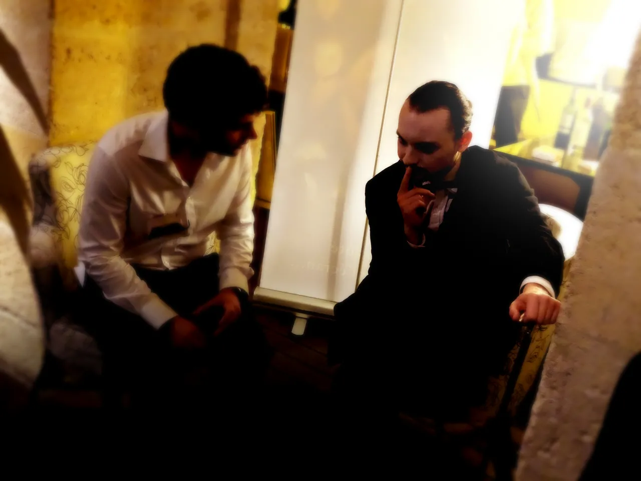Two men in business attire having a conversation in a narrow hallway with yellow-painted walls in Bordeaux