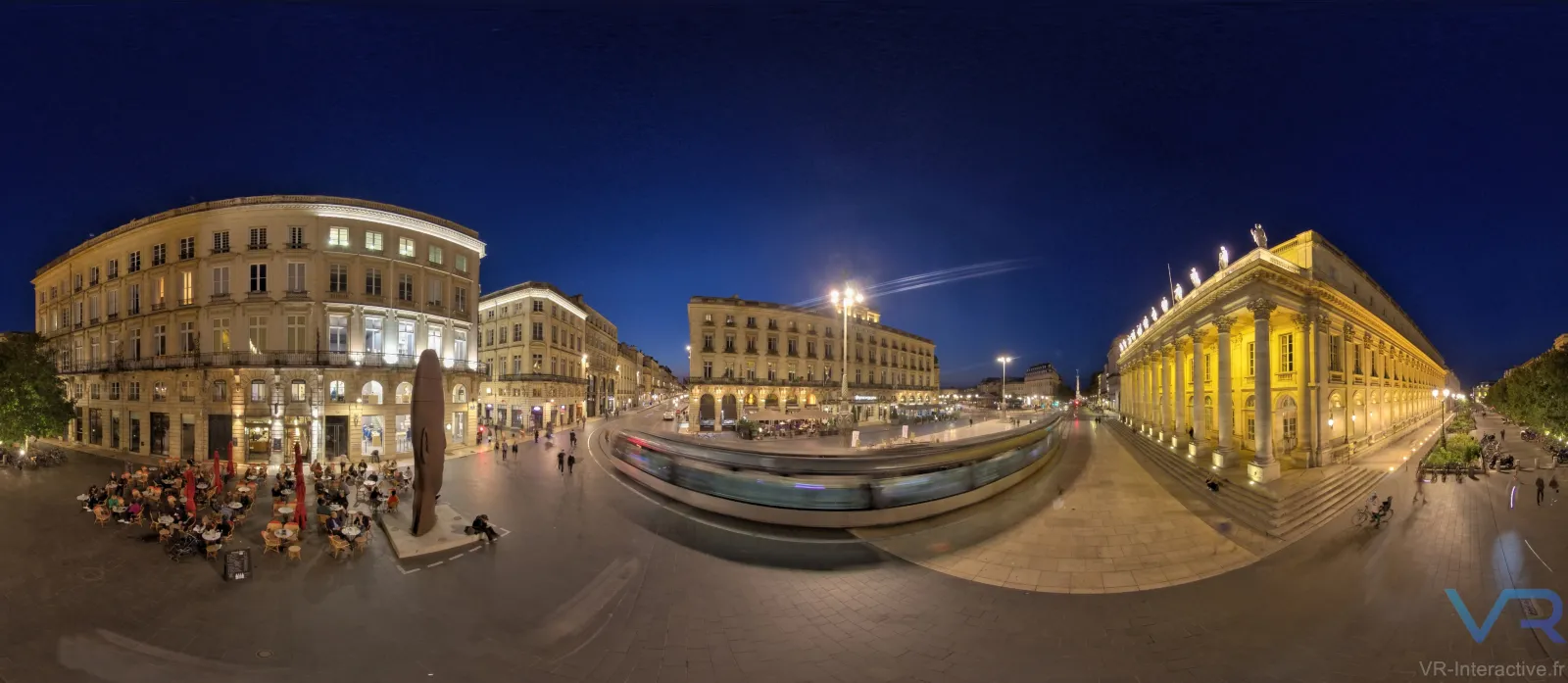 360-degree panoramic view of Place de la Comédie in Bordeaux at night, featuring illuminated classical buildings, a tram in motion, outdoor cafes, and pedestrians in the city center.