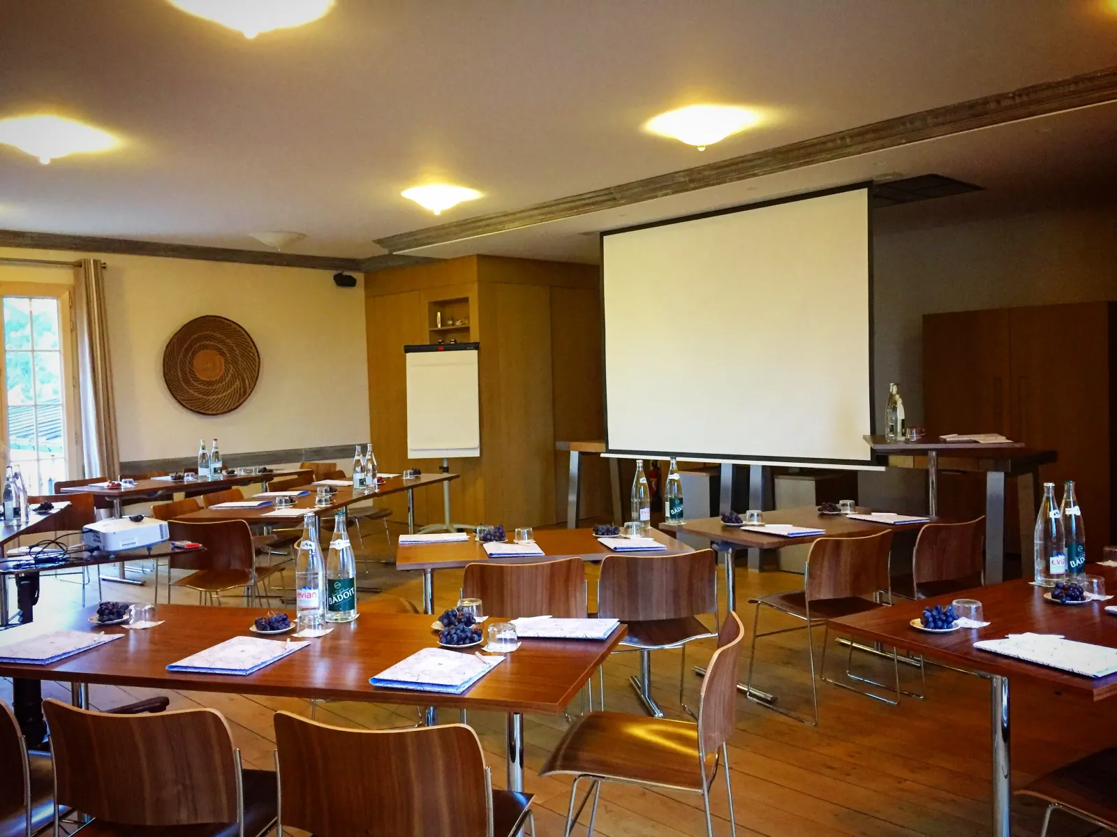 Modern conference room at Cézame Atlantique in Bordeaux with wooden tables, comfortable chairs, projection screen, and ambient lighting suitable for business meetings and presentations.
