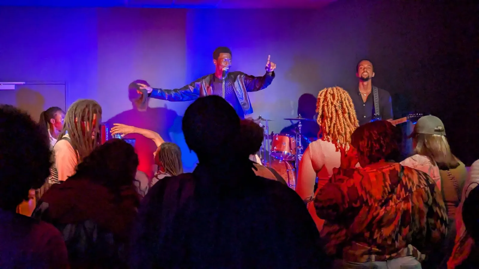 Live music performance on stage at L'Estrade in Bordeaux with two musicians performing in front of an engaged audience under purple and blue stage lighting
