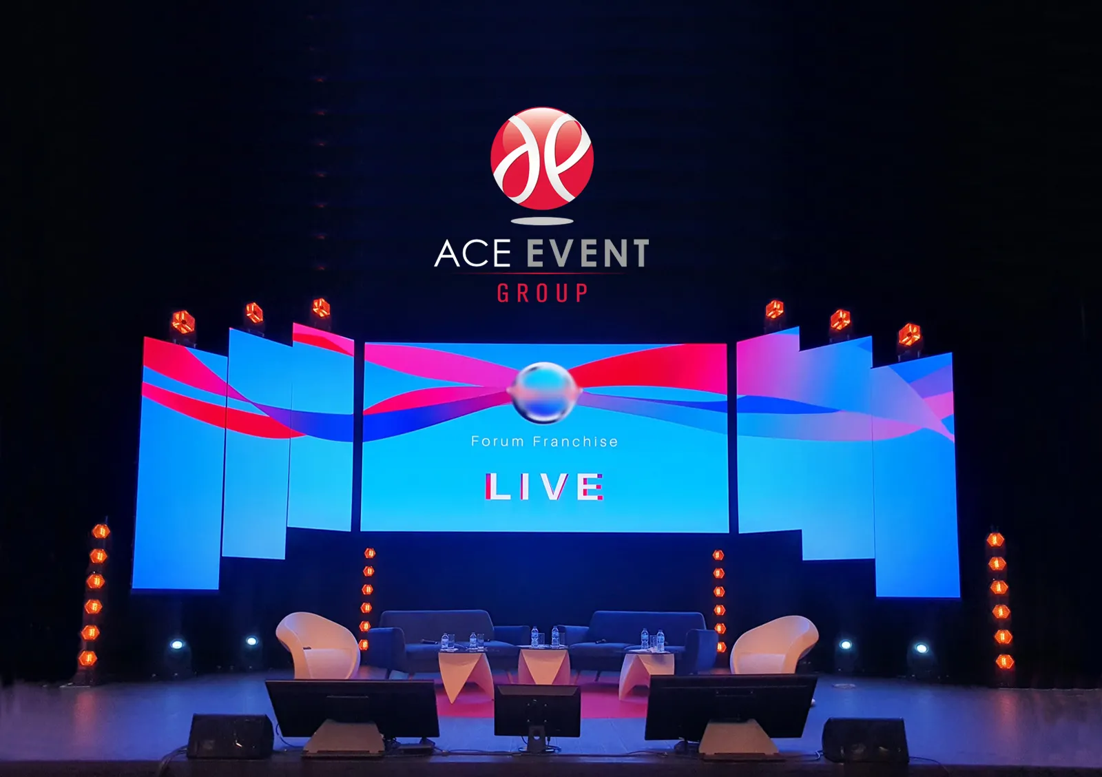 ACE EVENT GROUP stage setup for Forum Franchise Live event in Bordeaux, featuring a modern blue and pink digital display with basketball logo, professional seating area, and ambient lighting