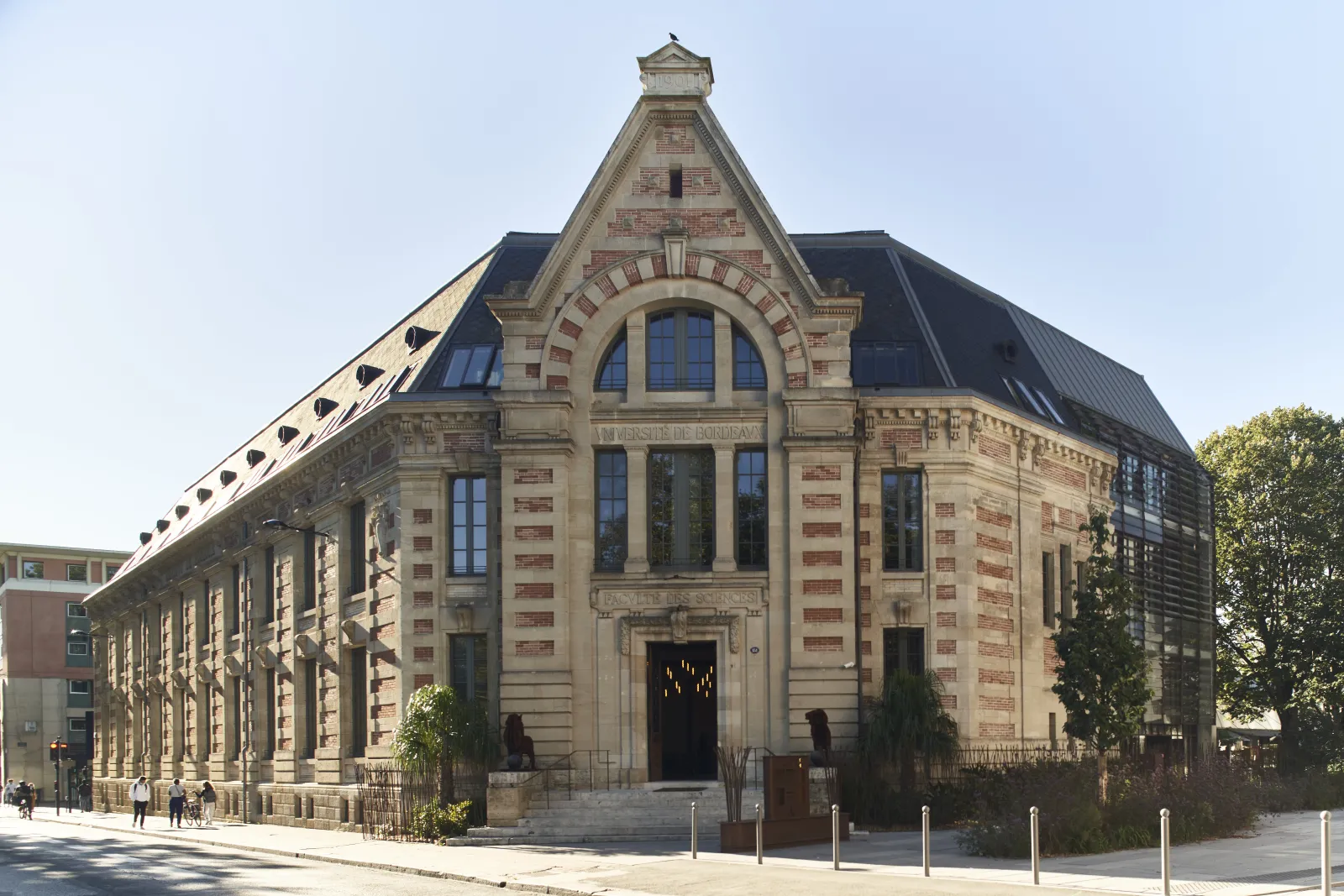 Historic Hôtel La Zoologie building in Bordeaux featuring Romanesque Revival architecture with cream and red stone facade, mansard roof with dormer windows, and large arched entrance