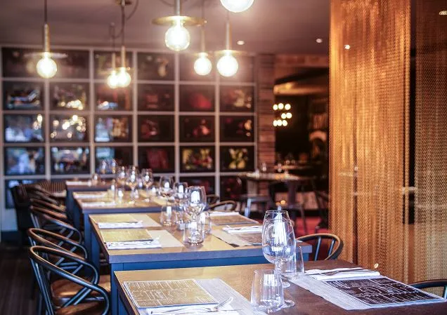 Modern conference room at Pullman Bordeaux Lac with a long blue table, place settings, water glasses, pendant lighting, and floor-to-ceiling windows overlooking the city.