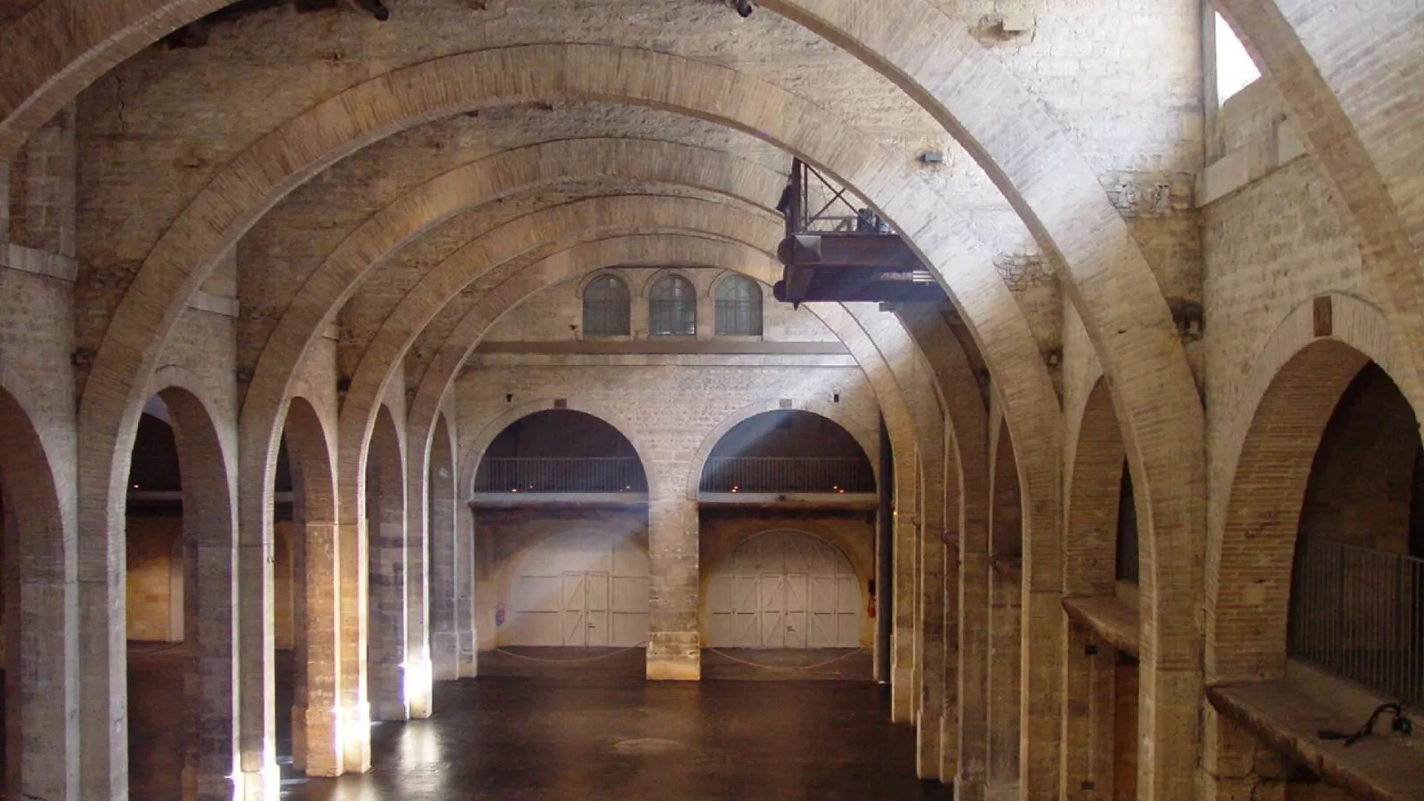 Interior of a brick warehouse with barrel-vaulted ceilings, multiple arches, and large doors, part of the CAPC Museum of Contemporary Art in Bordeaux