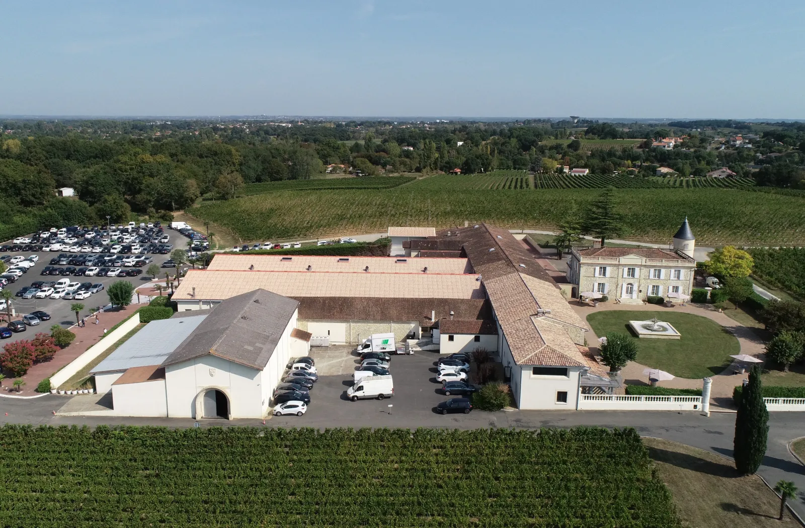 Aerial view of Château Lafite winery in Bordeaux, showing the main buildings, parking area, and surrounding vineyards in the Pauillac region