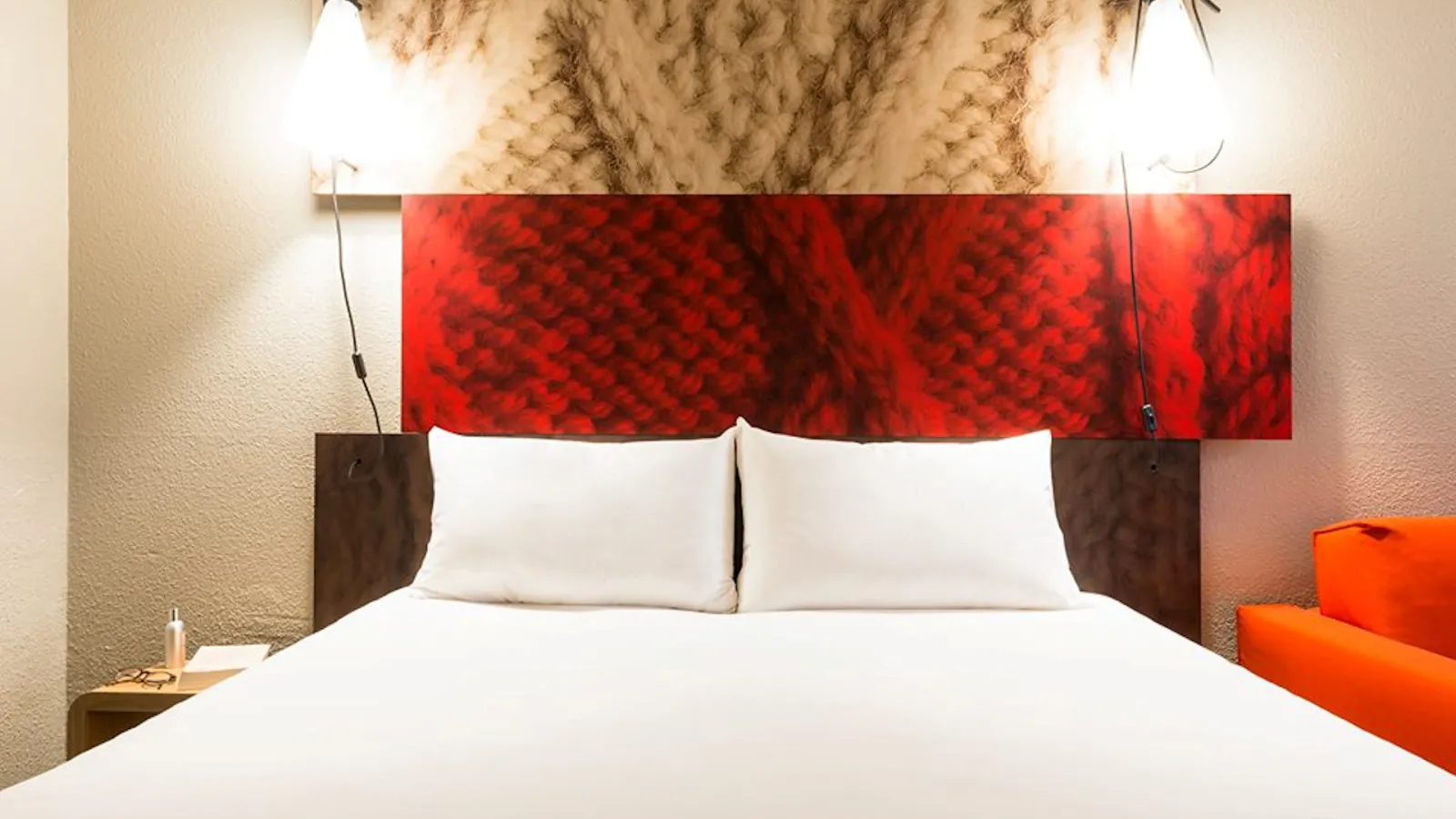 Modern hotel bedroom with white bed, white pillows, dark brown headboard panels, and vibrant red abstract artwork above the bed in the Ibis Bordeaux Centre Mériadeck hotel