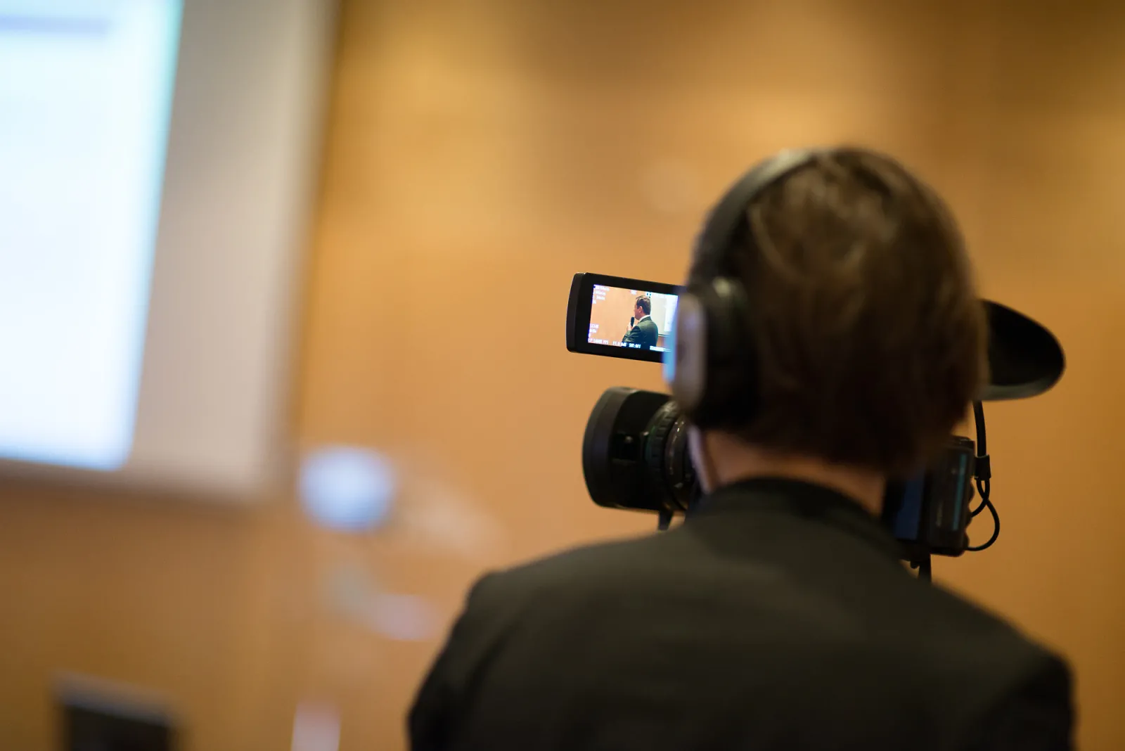 Person wearing headphones recording video content on a smartphone in a conference hall at Cézame Atlantique in Bordeaux