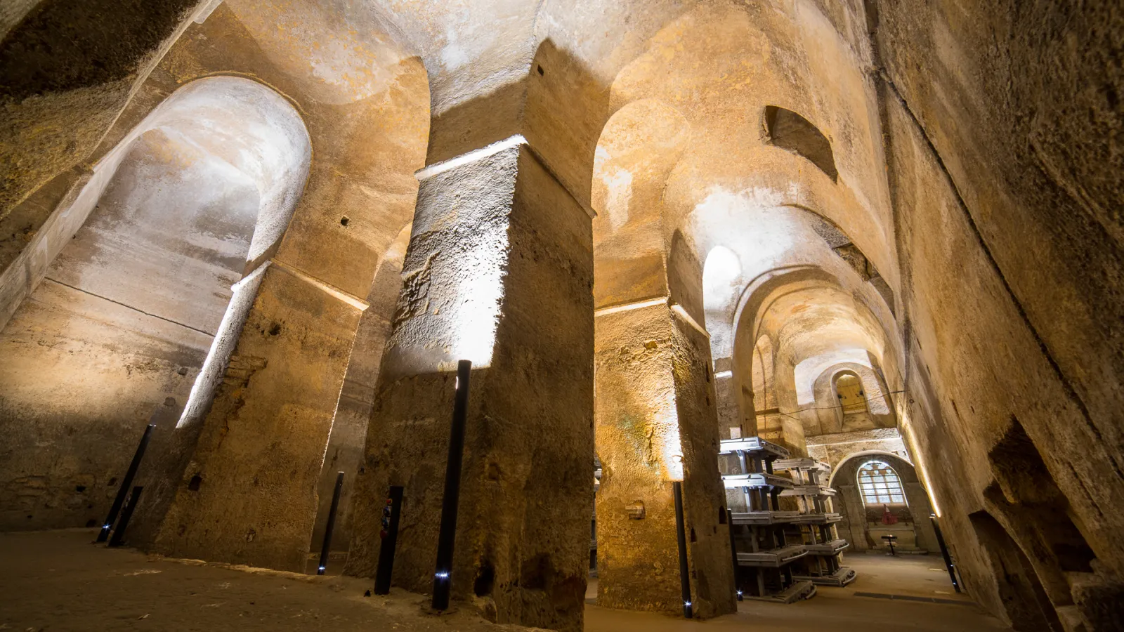 Interior of an ancient Roman basilica with massive stone columns, barrel vaults, and warm golden lighting, located in Bordeaux region