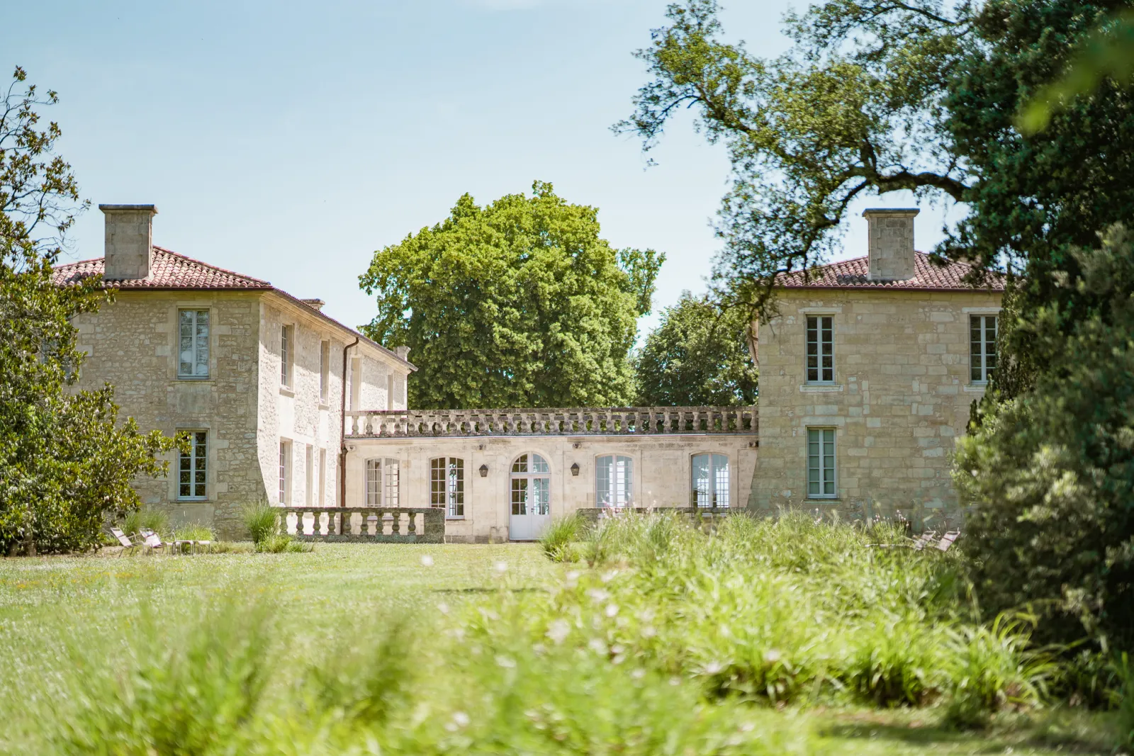 Château de Ferrand near Bordeaux, a stone manor house with two towers connected by a central wing, featuring classical balustrades and surrounded by manicured lawns and mature trees