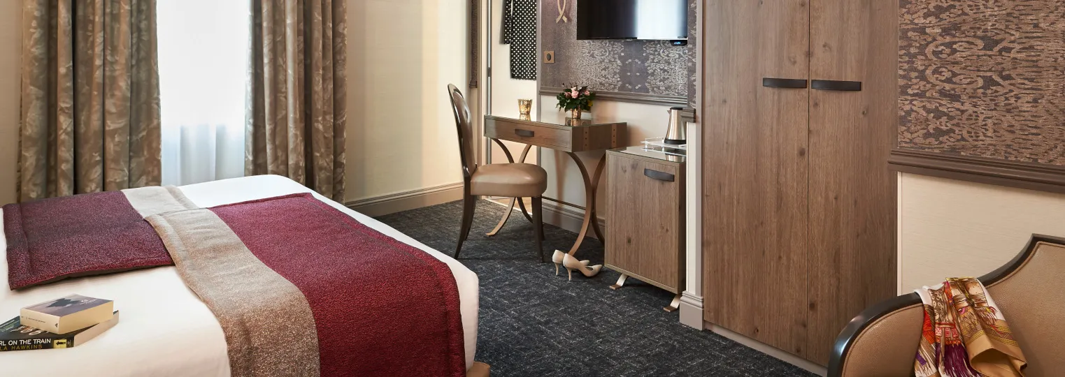 Elegant hotel room at Best Western Premier Hôtel Bayonne Etche Ona in Bordeaux, featuring a bed with burgundy bedding, wooden desk with chair, TV mounted on wall, and modern amenities
