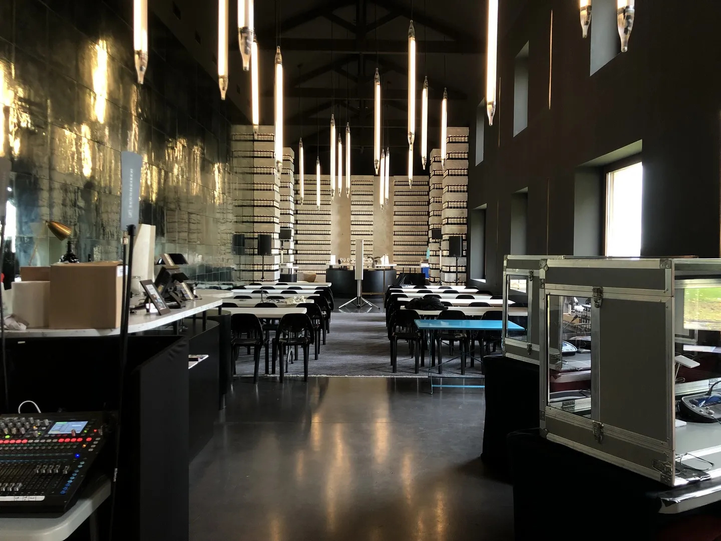 Modern conference hall in Bordeaux with black and white checkered floor, tall vertical lighting fixtures, brick walls, and professional seating areas with audiovisual equipment