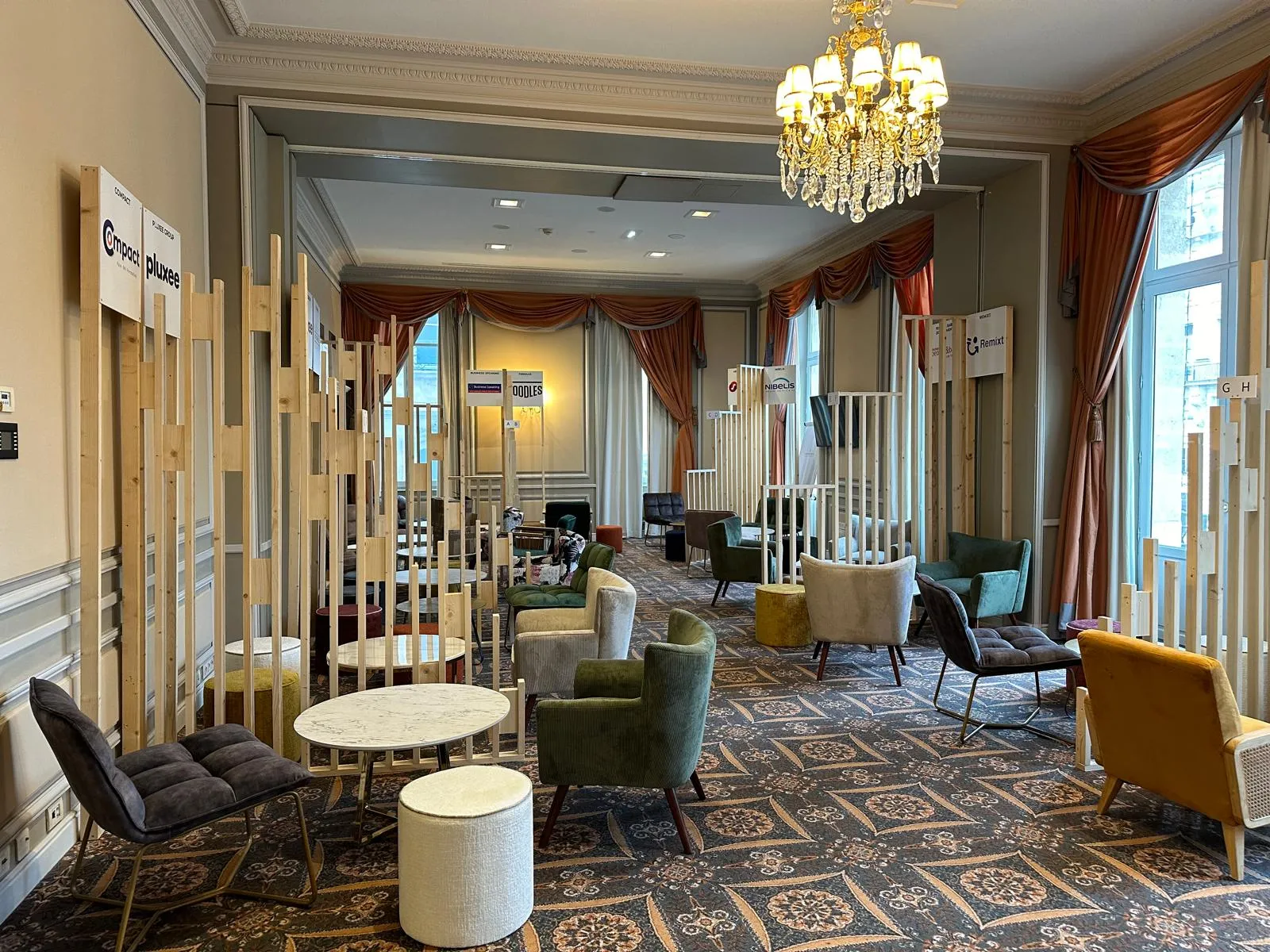Elegant showroom display in Bordeaux featuring flooring samples, furniture displays, and decorative elements with ornate chandeliers and burgundy drapery.