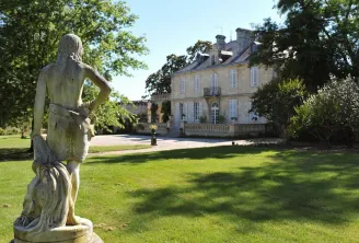 Stone statue of a female figure in the gardens of Château Kirwan in Bordeaux, with the 18th-century mansion visible in the background surrounded by trees