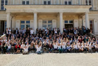 Large group photo of approximately 200 people gathered on the steps and courtyard of an elegant neoclassical building with white columns in Bordeaux, France.