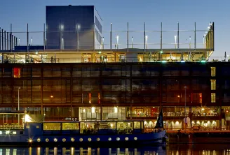 Modern Radisson Blu Hotel building in Bordeaux with illuminated glass and metal facade reflected in water at dusk, featuring contemporary architecture with distinctive lighting.