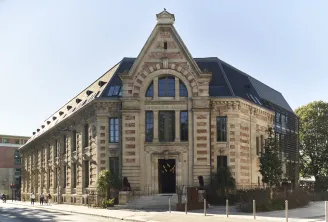 Historic Hôtel La Zoologie building in Bordeaux featuring Romanesque Revival architecture with cream and red stone facade, mansard roof with dormer windows, and large arched entrance