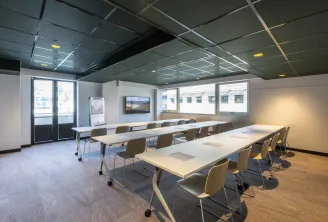 Modern conference room at Ibis Styles Bordeaux Meriadeck with mobile tables, ergonomic chairs, suspended ceiling with integrated lighting, large windows, and audiovisual equipment.