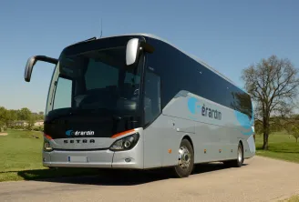 White and dark blue Setra coach bus with Gérardin branding parked on a country road near Bordeaux, with green meadows and trees in the background.
