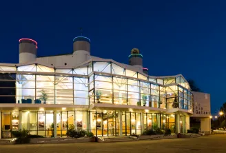 Modern glass and steel building illuminated at night with three cylindrical towers on the roof, located in Bordeaux's Pin Galant district