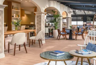 Modern hotel lobby and lounge area at Arcanse by Inwood in Bordeaux, featuring contemporary furniture, decorative arches, natural wood elements, green plants, and ambient lighting