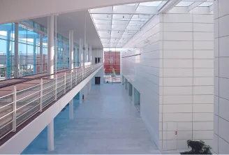 Interior corridor of Bordeaux Congress Centre with modern white tile walls, skylight ceiling, metal railings, and large windows overlooking the city skyline