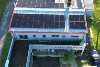 Aerial view of Deval Traiteur's facility in Bordeaux featuring a blue and red building with extensive solar panels installed on the roof, demonstrating sustainable business practices.