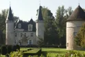 Château d'Agassac in Bordeaux, France, featuring a white stone castle with two tall towers with black pointed roofs, a central mansard roof, and a separate round tower on the right, surrounded by manicured gardens and trees.