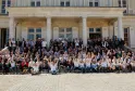 Large group photo of approximately 200 people gathered on the steps and courtyard of an elegant neoclassical building with white columns in Bordeaux, France.
