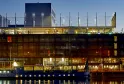 Modern Radisson Blu Hotel building in Bordeaux with illuminated glass and metal facade reflected in water at dusk, featuring contemporary architecture with distinctive lighting.