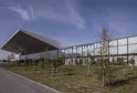 Modern glass and steel exhibition hall with 'Palais 2 L'Atlantique' signage, surrounded by young trees and landscaping in Bordeaux.